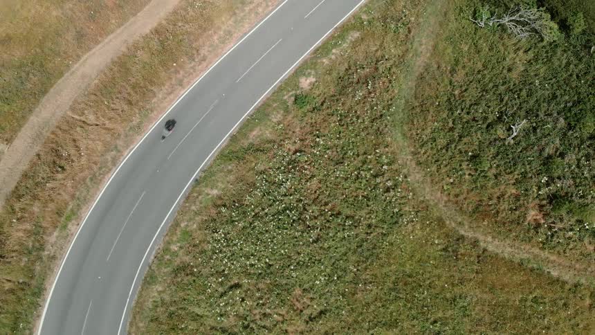 A bike is riding alone a curvy road