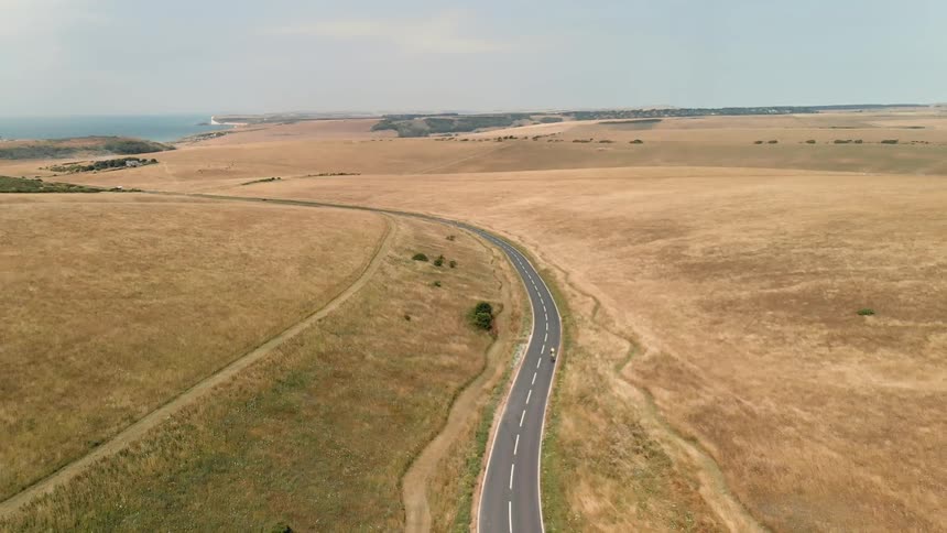 A person bikes on a long winding road