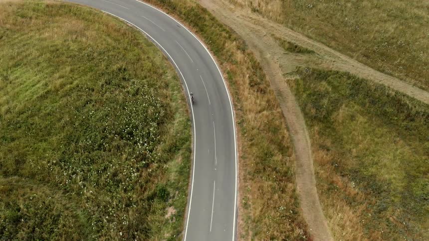 Bike riders travel on a curving rural road