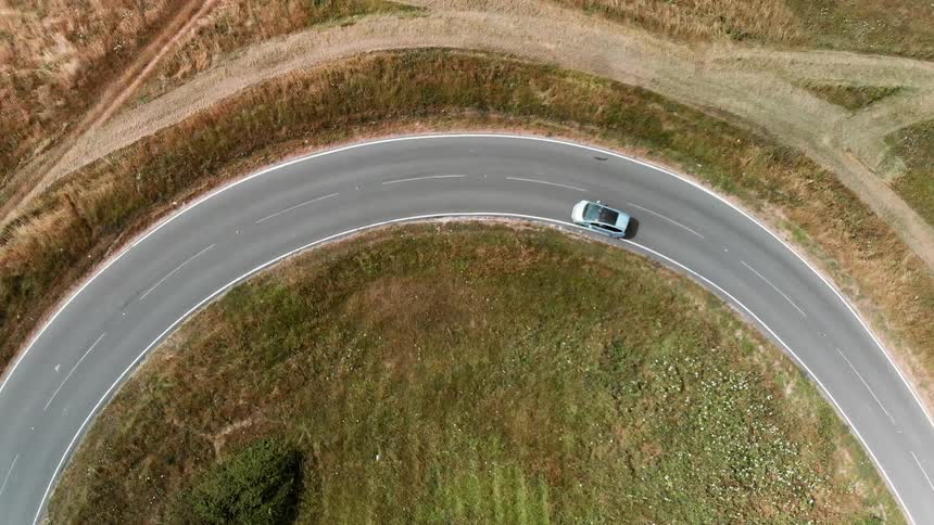 A car travels around a curve on a rural road