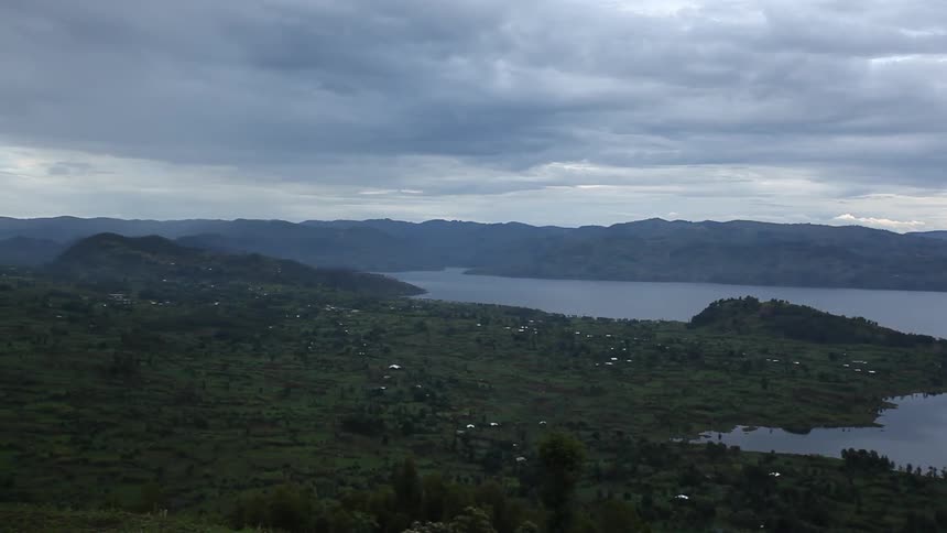 Aerial view of some green fields by the water on a cloudy day
