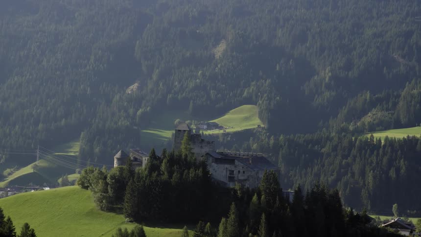 A villa sits atop a hillside in a forested area