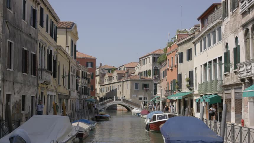 Moving view of going down a river between buildings in italy