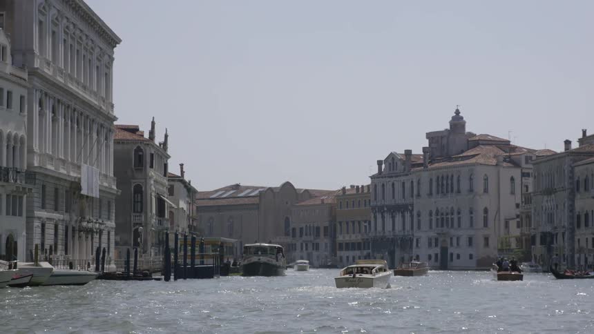 Several boats are in a harbor lined with tall buildings