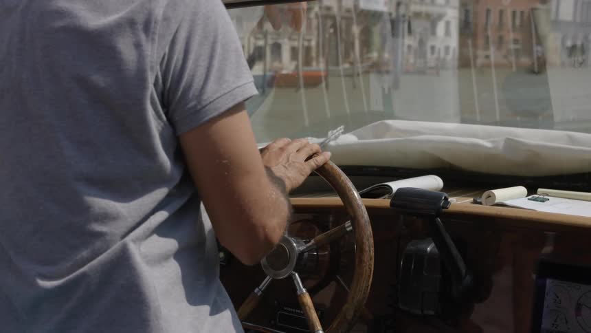 A person drives a boat on a canal