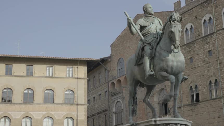 A statue of a man on a horse stands in an old city plaza