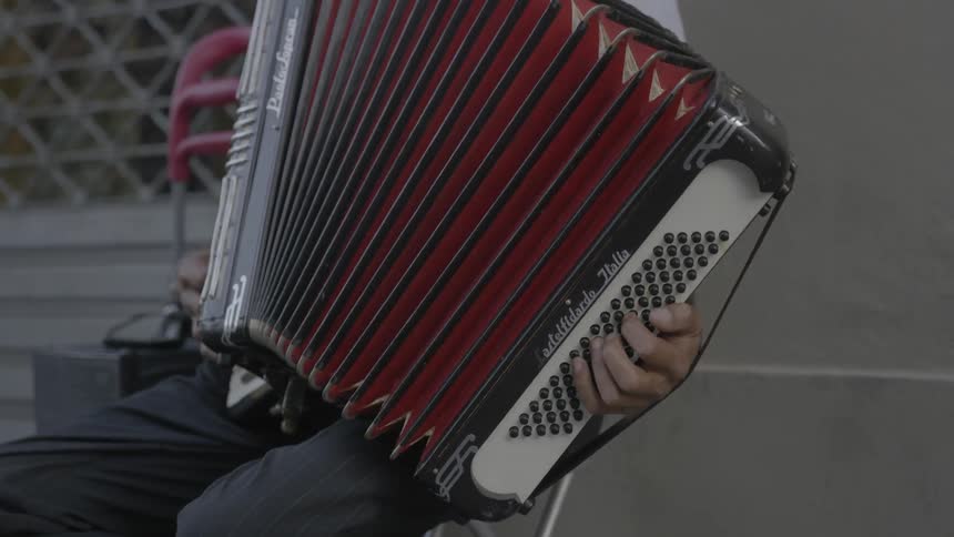 A man is sitting and playing the accordion