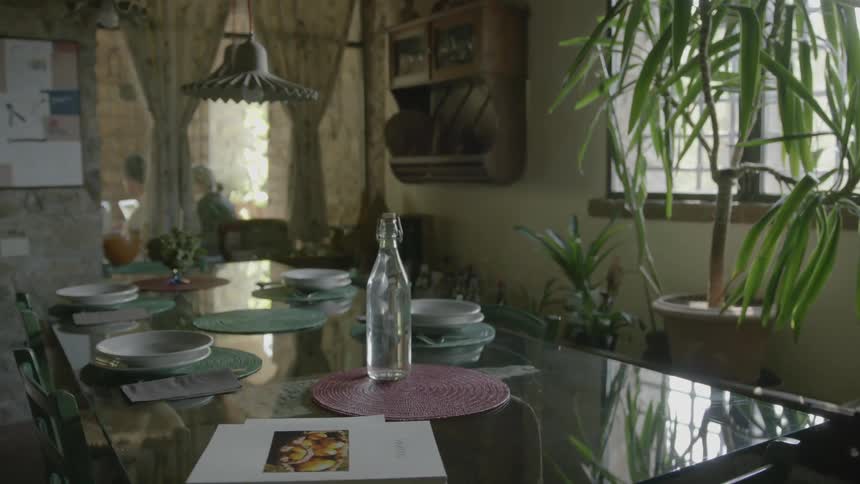 A glass bottle sits on a set table