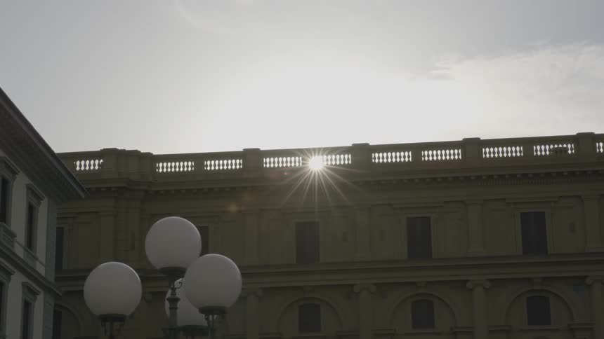 The sun is shining over the top of an old, large building