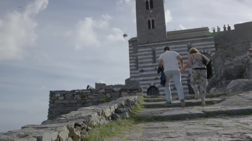 A man and woman are walking up a stone pathway toward an old building