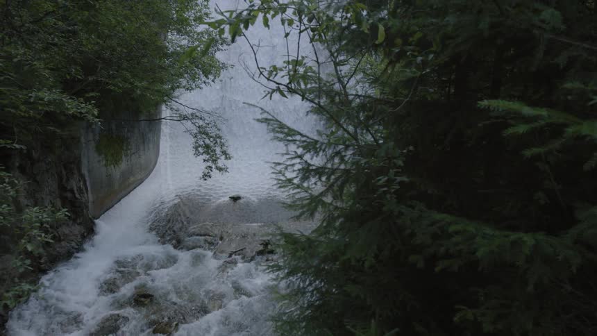 A river streams over a steep drop and boulders in a gorge