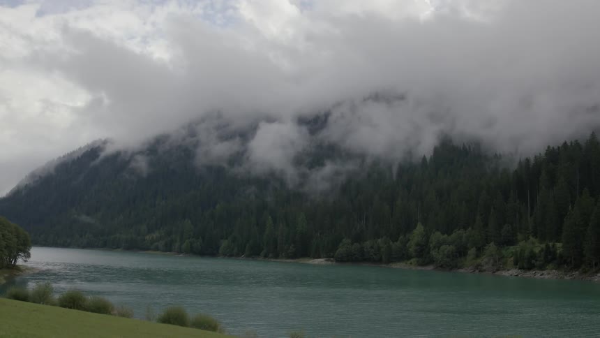 A scene of a mountain that is smokey and is next to a river