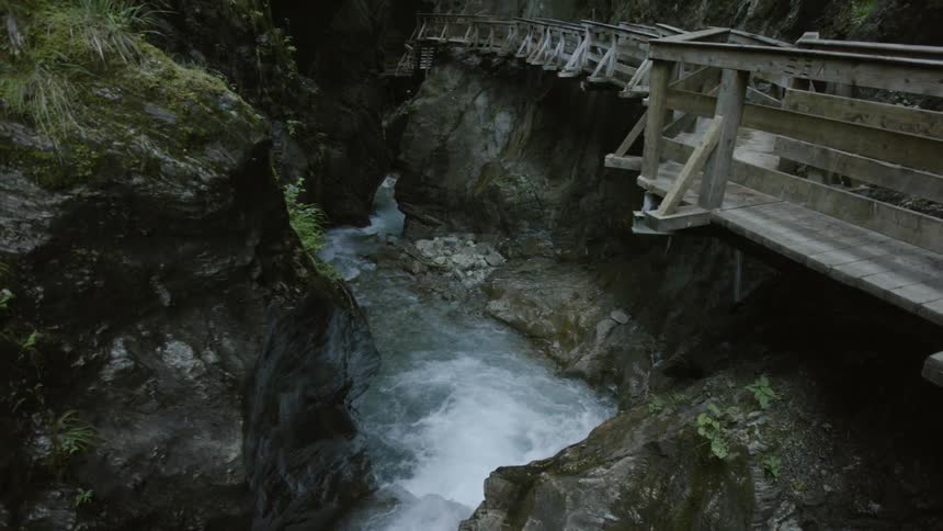Aerial view of waters flowing  in a river below a bridge
