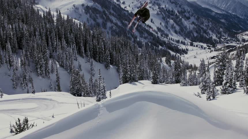 A skier jumps from a snow ramp on a slope