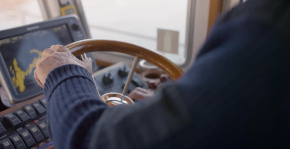 A person is steering a boat with a display in front of him