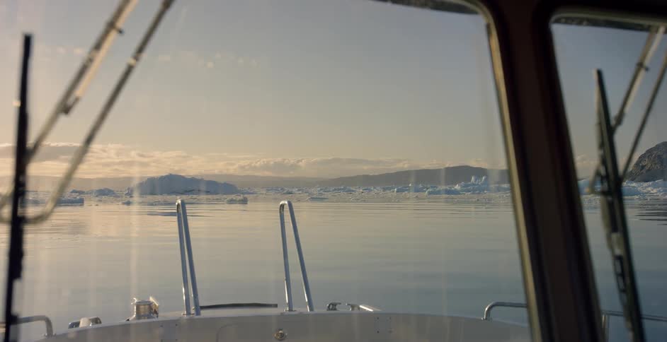 Icebergs float off the bow of ship during the day