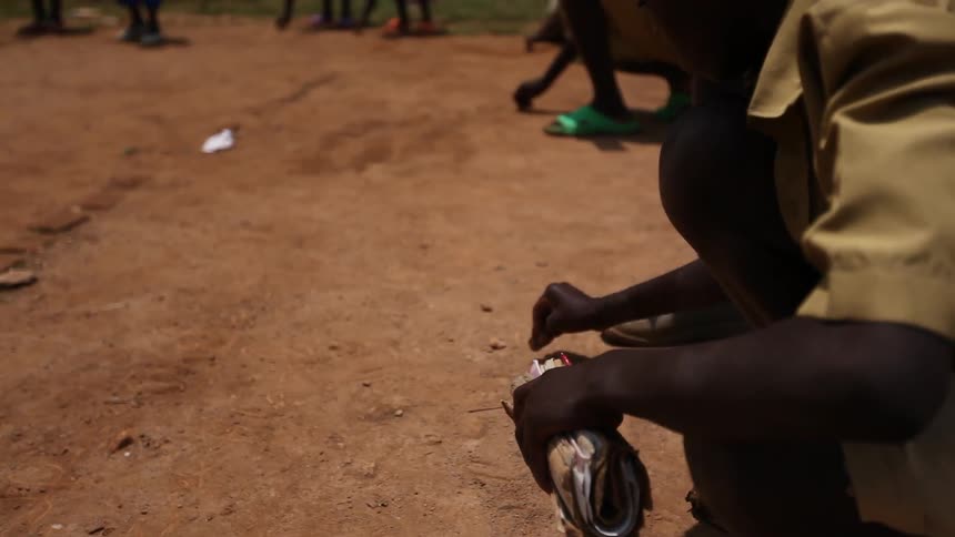 African boys are planting seeds into the ground of a garden area