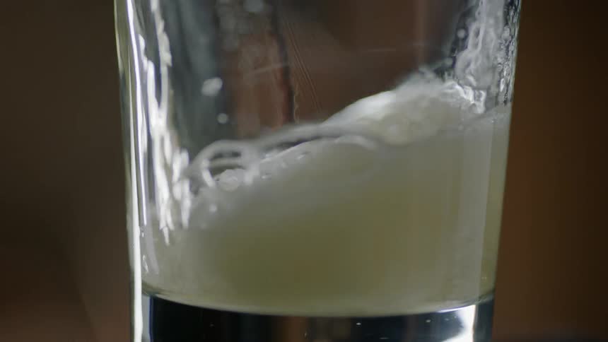 A foamy liquid is poured into a glass