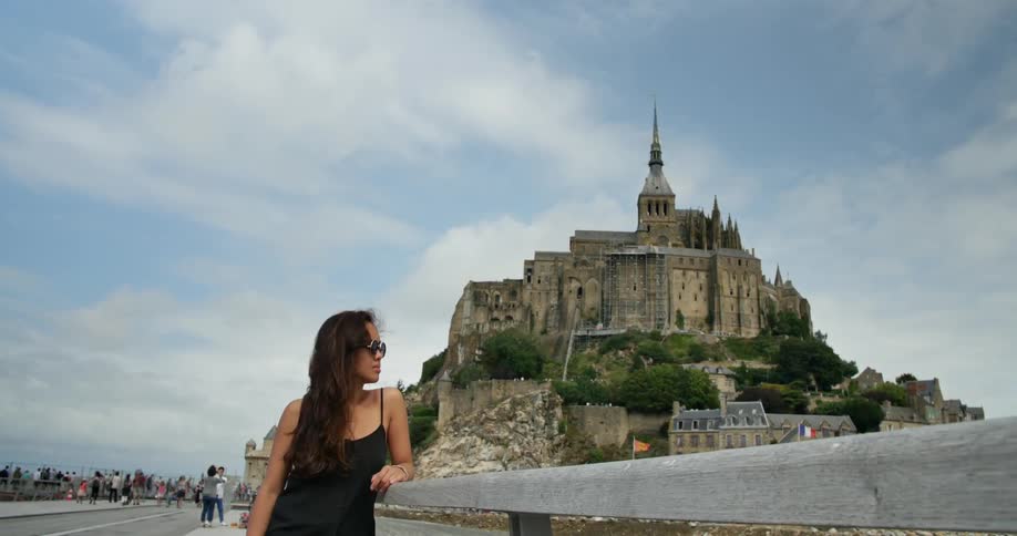 A woman poses in front of a hilltop building