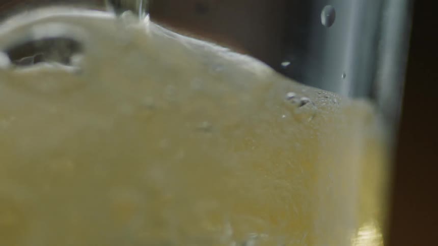 A foamy liquid is poured into a glass