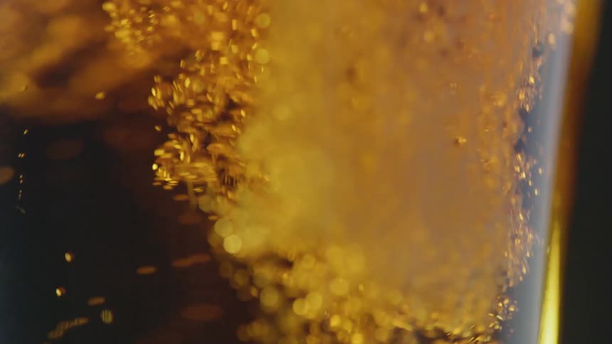 Beer is being poured into a glass and its making bubbles