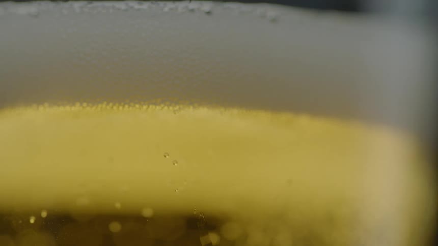 Beer foams at the rim of a glass