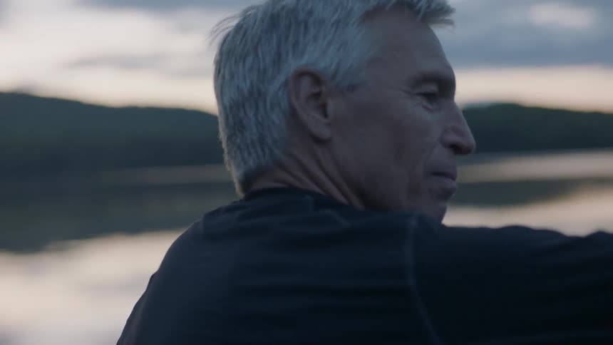 A man takes in the view by the lake at sunset