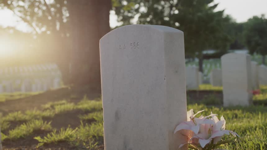 A tombstone has white flowers next to it