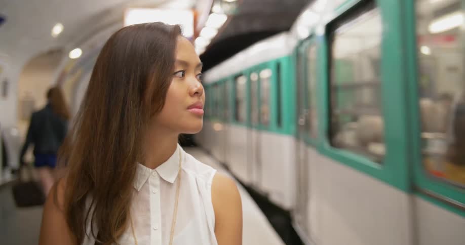 Woman stands on a platform as a train arrives