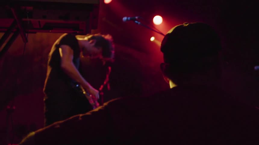 Man playing guitar under red lights on concert stage