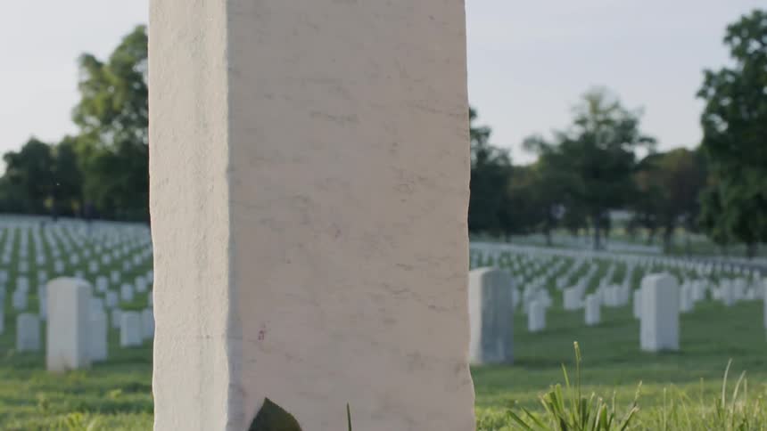Woman places flowers by a grave