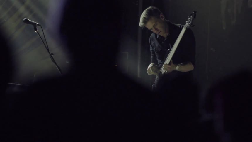Man playing guitar on concert stage under flashing lights