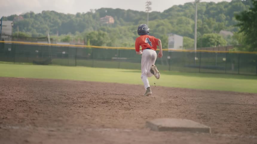 A little league player runs for second base after a hit