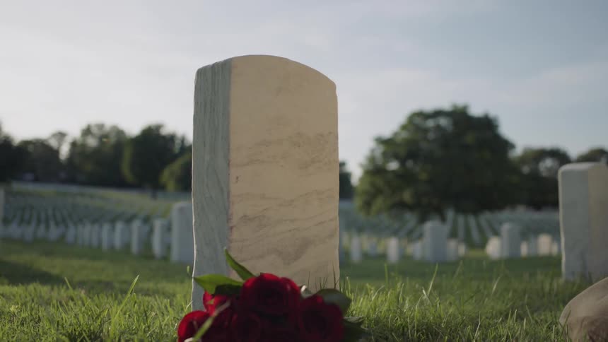 Woman places flowers by a grave