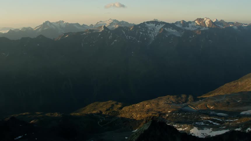Patches of snow covered mountain peaks at sunset