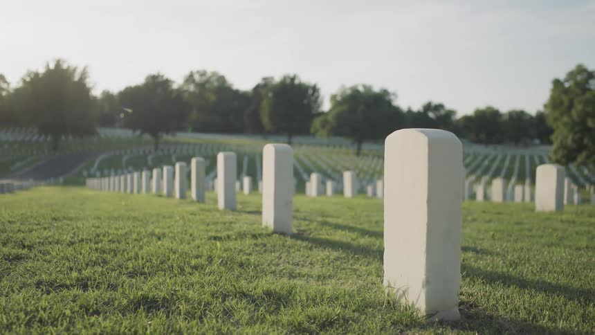Rows of white headstones in a cemetery on a sunny day
