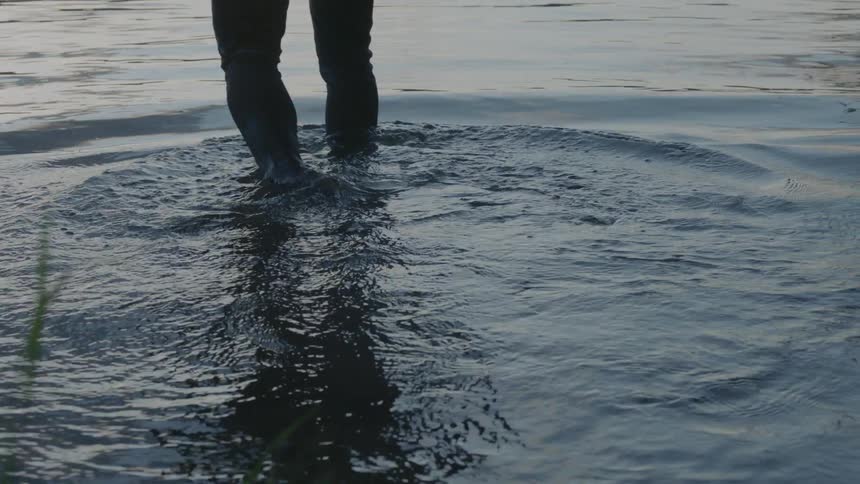 A person walks into a lake