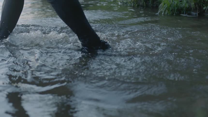 A person is walking into a lake