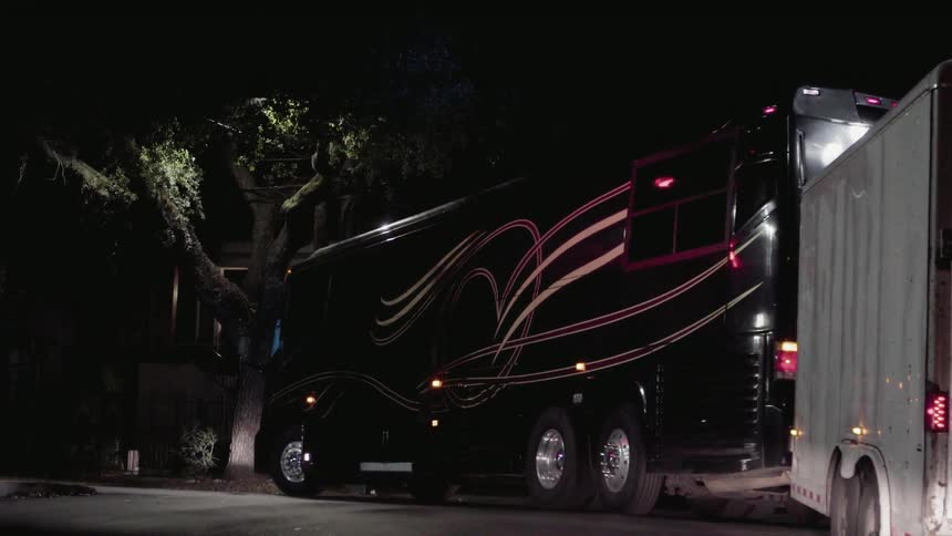 A bus pulls a trailer behind it at night
