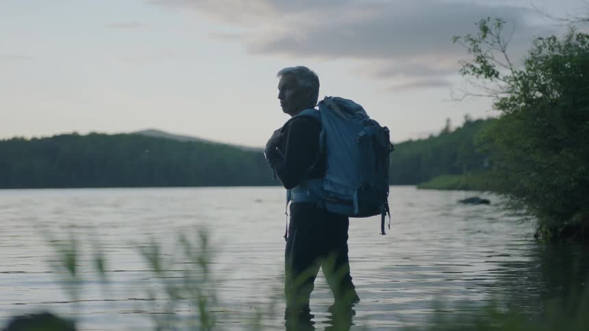 Man with backpack stands in a pond