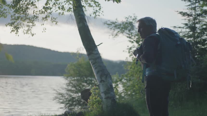 A man carrying a backpack stands by the lake