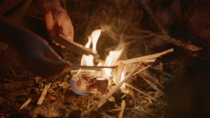 Person starts a small fire outside at night