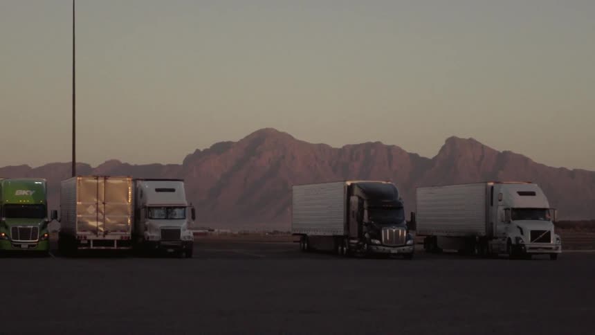 Trucks are parked at a rest stop near the mountains