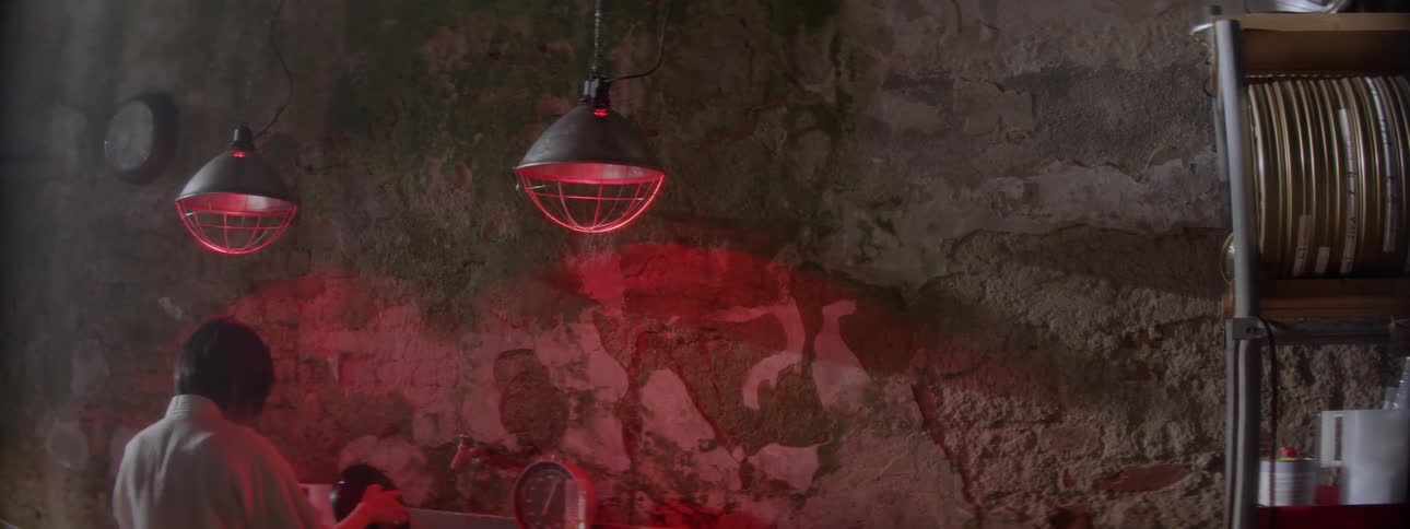 The room is dark with red lights hanging from the ceiling