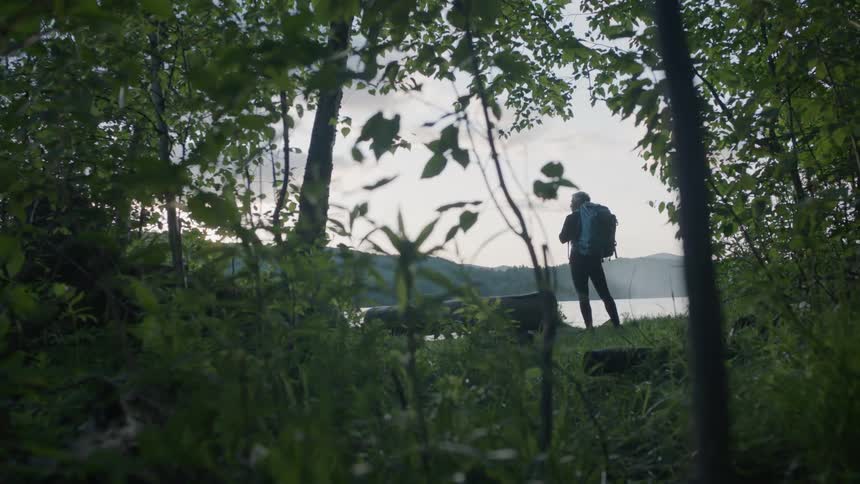 Hiker stands next to a mountain lake
