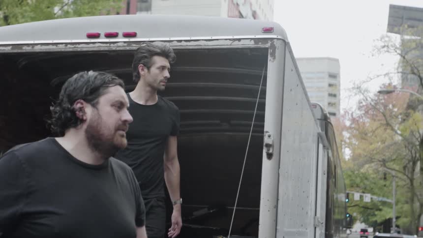 Men in black step out of a moving van