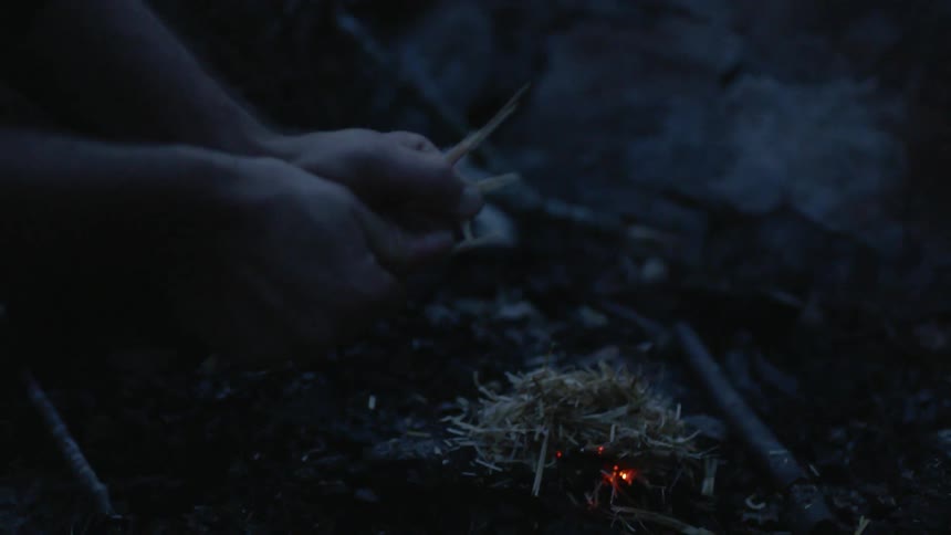 Man breaks sticks to start a fire