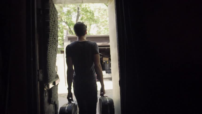 Musician carries his guitars towards a shed