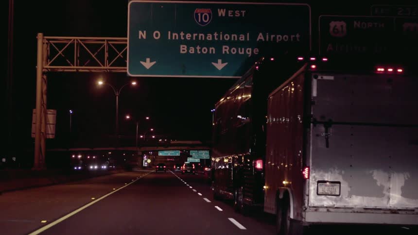 A bus pulls a trailer on a freeway at night