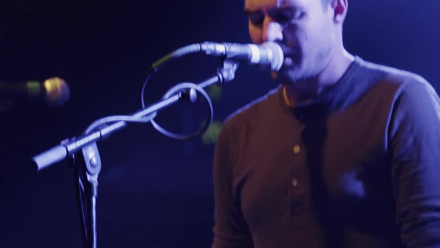 A man plays a keyboard and sings at a concert